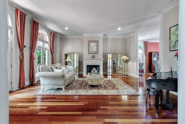 living area with recessed lighting, a fireplace, crown molding, decorative columns, and wood finished floors