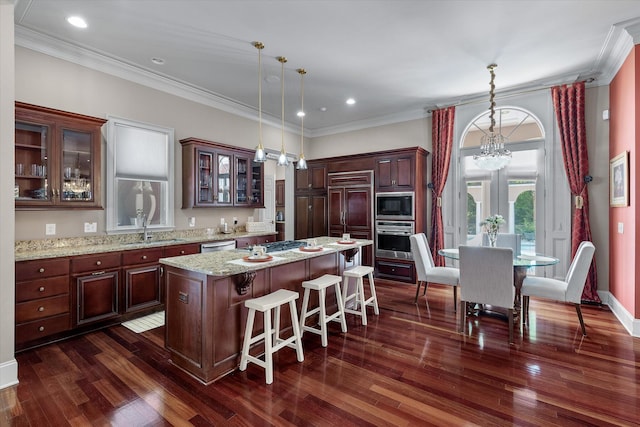 kitchen with built in appliances, dark wood-style flooring, glass insert cabinets, a kitchen island, and a breakfast bar area
