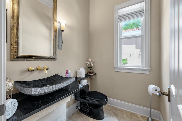 half bath with a sink, baseboards, and toilet