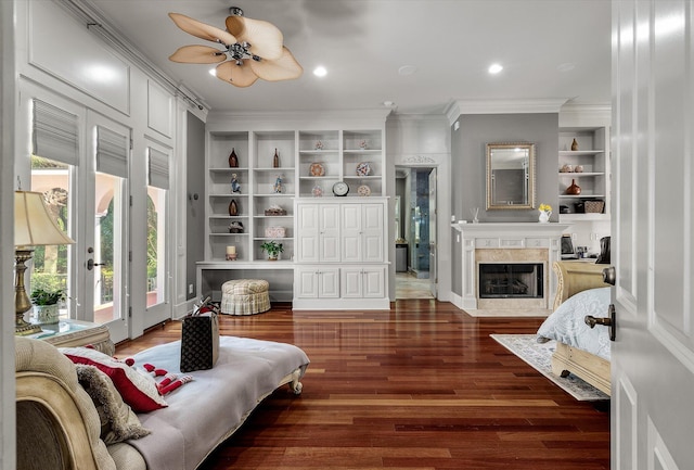 living room featuring built in features, ornamental molding, ceiling fan, a high end fireplace, and wood finished floors