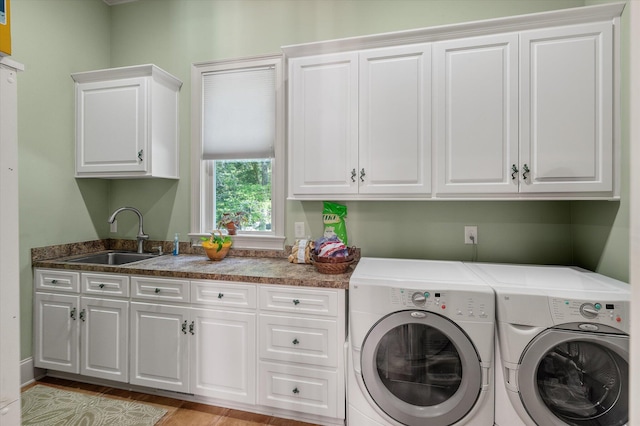 laundry area with independent washer and dryer, a sink, and cabinet space
