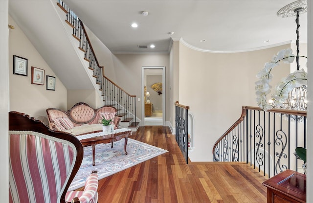 living area featuring visible vents, an upstairs landing, crown molding, recessed lighting, and wood finished floors