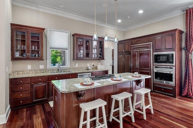 kitchen with built in appliances, a kitchen breakfast bar, glass insert cabinets, a center island, and dark wood-style floors