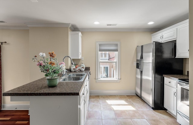 kitchen with ornamental molding, white cabinetry, dark countertops, appliances with stainless steel finishes, and a sink