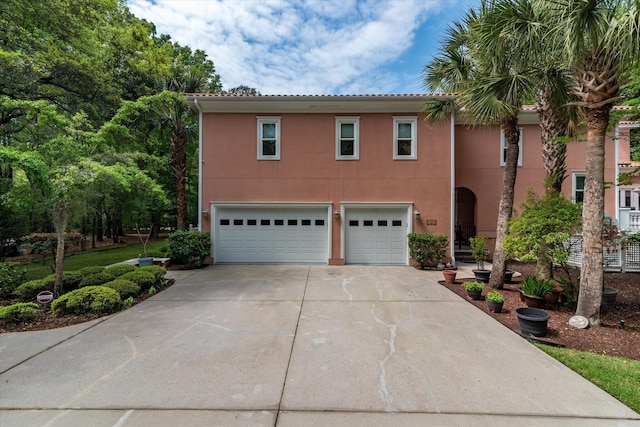 mediterranean / spanish home featuring an attached garage, concrete driveway, and stucco siding