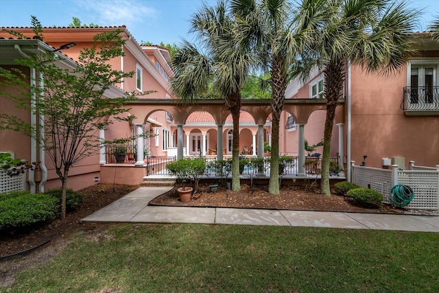 rear view of property with stucco siding, fence, and a lawn