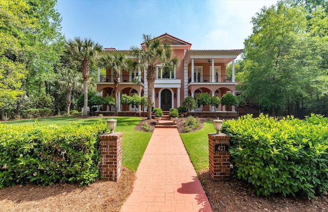 view of front of property featuring a front yard, stucco siding, and a balcony