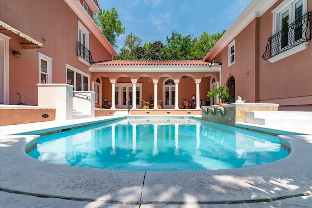 outdoor pool with a patio and french doors