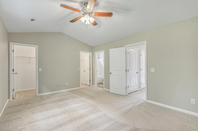 unfurnished bedroom featuring light carpet, ceiling fan, a closet, a spacious closet, and ensuite bathroom