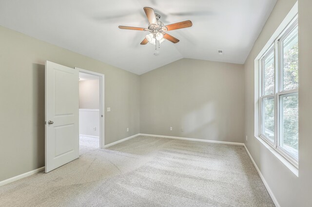 empty room featuring lofted ceiling, ceiling fan, and light colored carpet