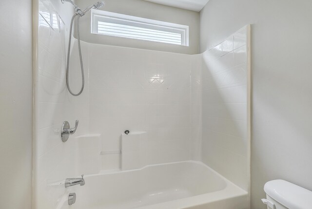 bathroom featuring toilet and tiled shower / bath