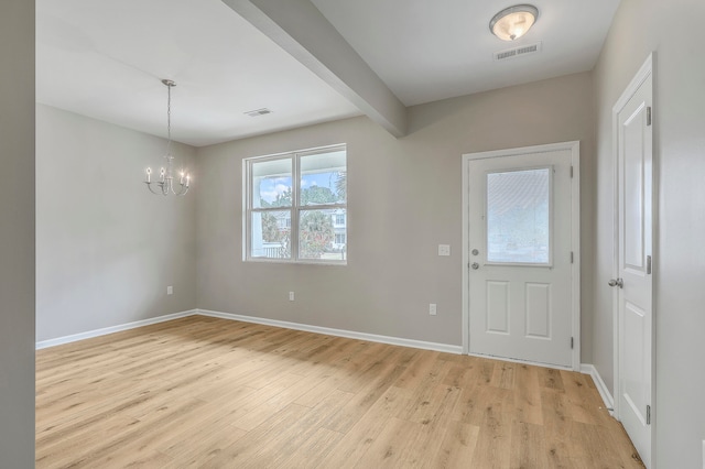 foyer entrance with light hardwood / wood-style flooring, beam ceiling, and a notable chandelier