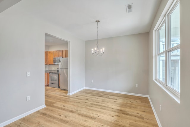 empty room with a chandelier and light hardwood / wood-style floors