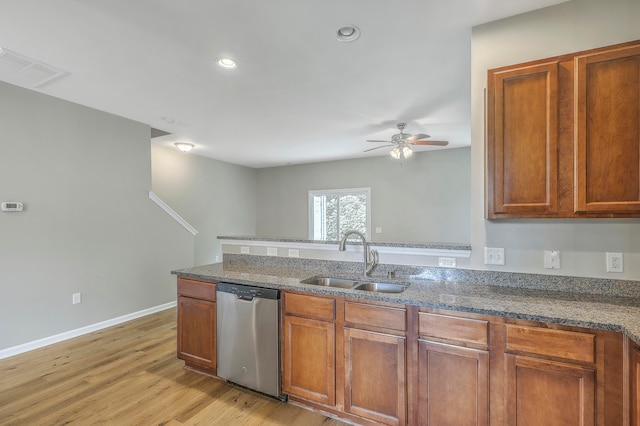 kitchen featuring light wood-type flooring, dark stone counters, dishwasher, sink, and ceiling fan