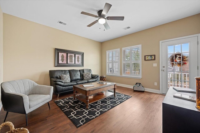 living area with visible vents, plenty of natural light, baseboards, and wood finished floors