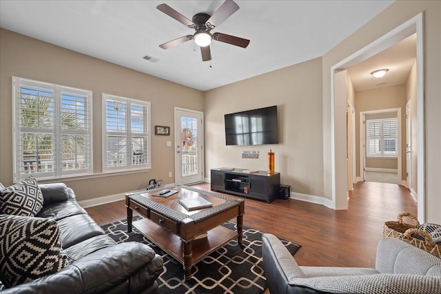 living area featuring a ceiling fan, visible vents, baseboards, and dark wood-style flooring