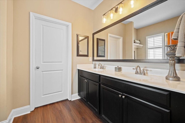 bathroom featuring double vanity, a sink, baseboards, and wood finished floors