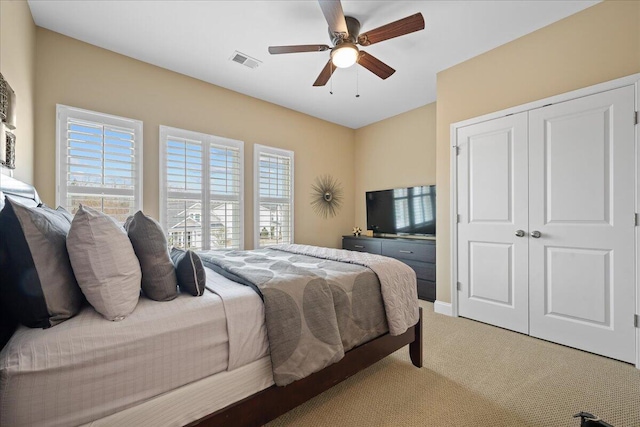 bedroom featuring a ceiling fan, light colored carpet, a closet, and visible vents