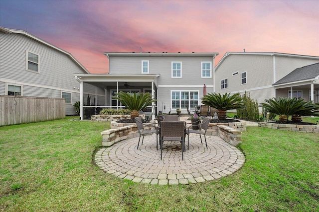 back of property at dusk with a lawn, a patio area, fence, and a ceiling fan