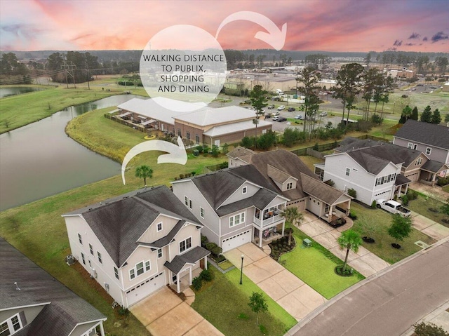 aerial view at dusk with a water view and a residential view