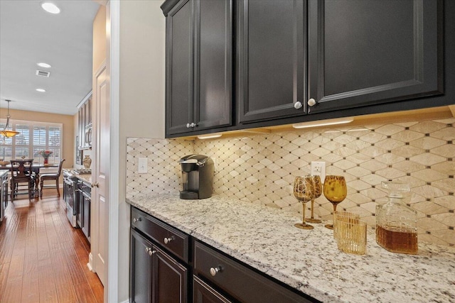 kitchen with light stone counters, dark wood finished floors, stainless steel appliances, visible vents, and backsplash