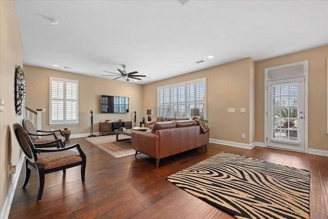 living room with dark wood-style floors, visible vents, and baseboards