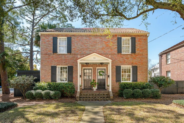 colonial home featuring brick siding and fence