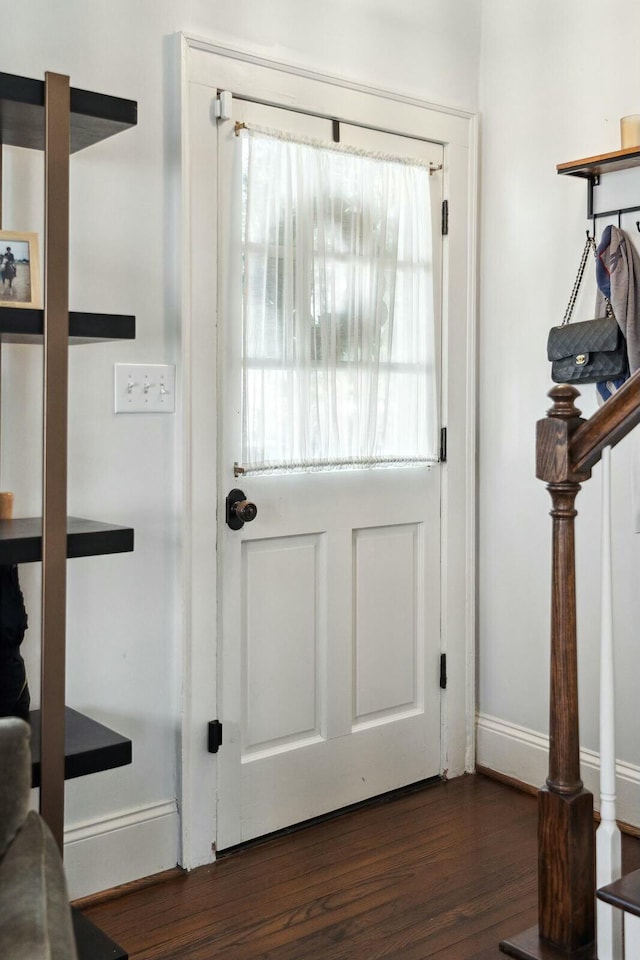 entryway featuring baseboards, wood finished floors, and stairs