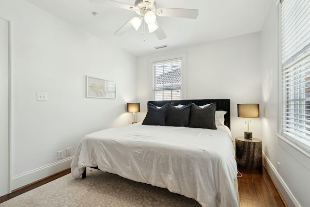 bedroom featuring visible vents, a ceiling fan, baseboards, and wood finished floors