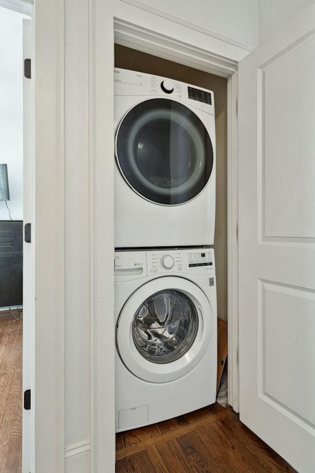 laundry room featuring laundry area, dark wood-type flooring, and stacked washing maching and dryer