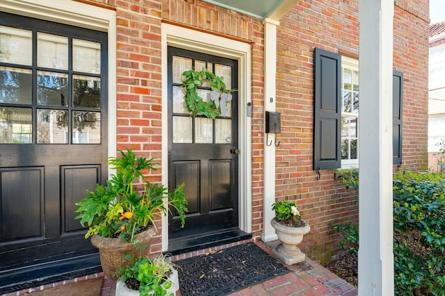 entrance to property with brick siding and a porch