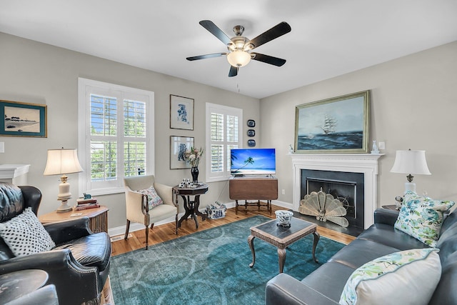 living room with baseboards, a ceiling fan, wood finished floors, and a fireplace