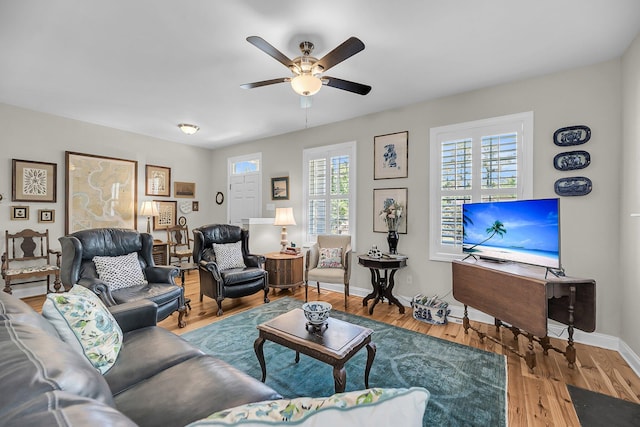 living area with baseboards, a ceiling fan, and wood finished floors