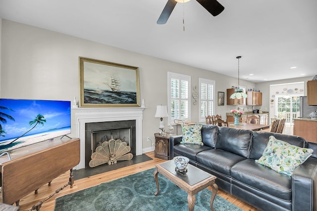 living room with recessed lighting, a fireplace with flush hearth, a ceiling fan, and wood finished floors