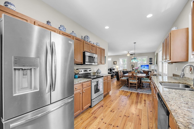 kitchen with brown cabinetry, appliances with stainless steel finishes, a sink, recessed lighting, and light wood-style flooring