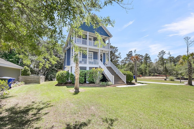rear view of house with a yard, stairway, a balcony, and a porch