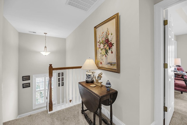 hall with baseboards, carpet, an upstairs landing, and visible vents