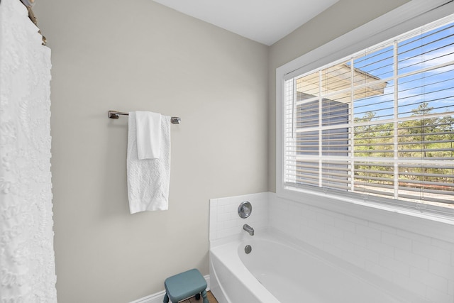 full bathroom with baseboards, a wealth of natural light, and a garden tub