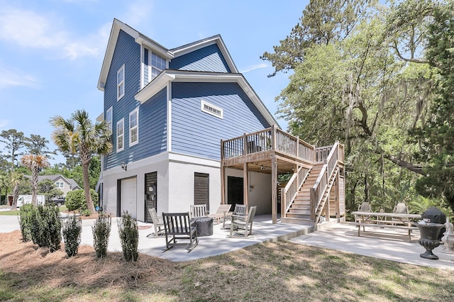 rear view of property with a deck, stucco siding, a patio area, an attached garage, and stairway