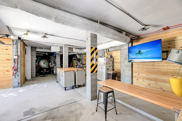 basement with wooden walls and freestanding refrigerator