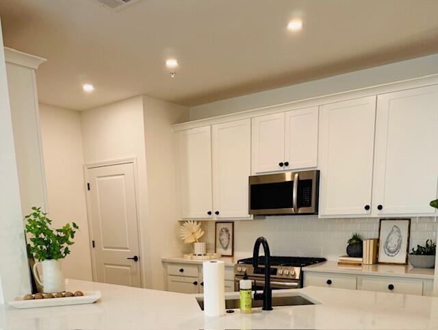 kitchen featuring white cabinetry, stainless steel appliances, and backsplash