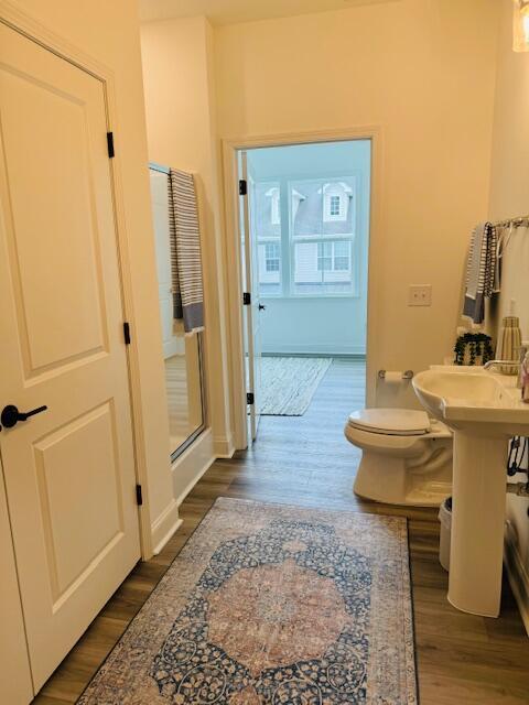 bathroom with hardwood / wood-style flooring, toilet, and a shower with door