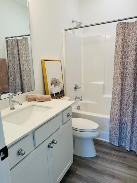 full bathroom with toilet, vanity, wood-type flooring, and shower / bathtub combination with curtain