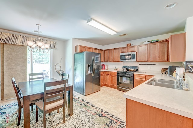 kitchen featuring pendant lighting, appliances with stainless steel finishes, sink, and a notable chandelier