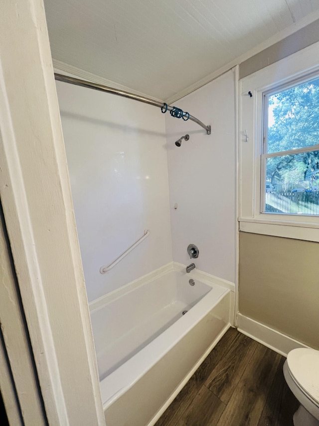 bathroom featuring wood-type flooring, tub / shower combination, and toilet