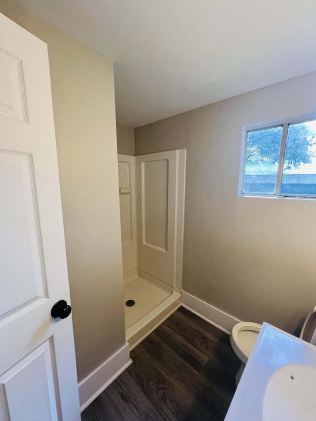 bathroom featuring baseboards, toilet, a stall shower, wood finished floors, and a sink