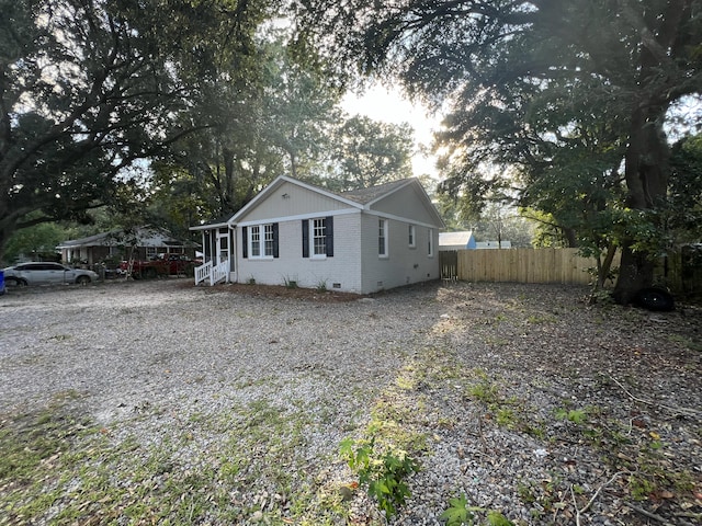 exterior space with crawl space, brick siding, gravel driveway, and fence