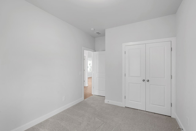 unfurnished bedroom featuring light colored carpet and a closet