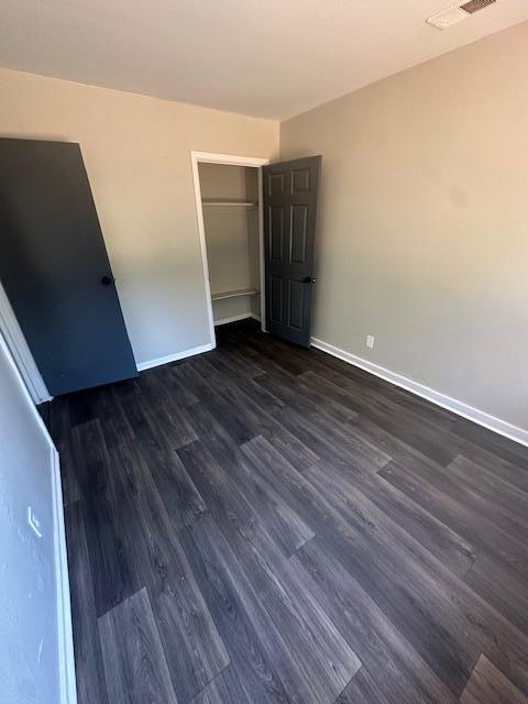 unfurnished bedroom with dark hardwood / wood-style flooring and a closet