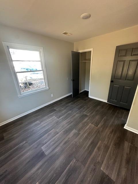 unfurnished bedroom featuring dark hardwood / wood-style flooring and a closet